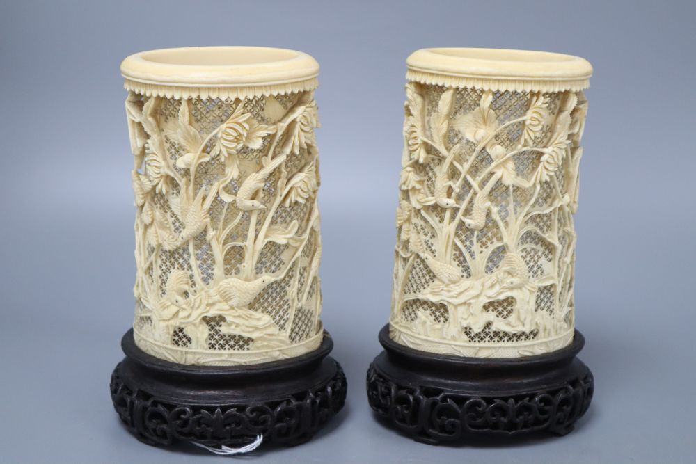 A pair of Japanese carved and pierced ivory brush pots, on hardwood stands, height 20cm
